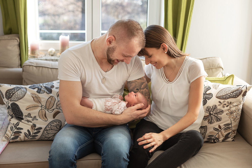 eine glueckliche Familie mit Baby bei einem Neugeborenen Fotoshooting in Muenchen